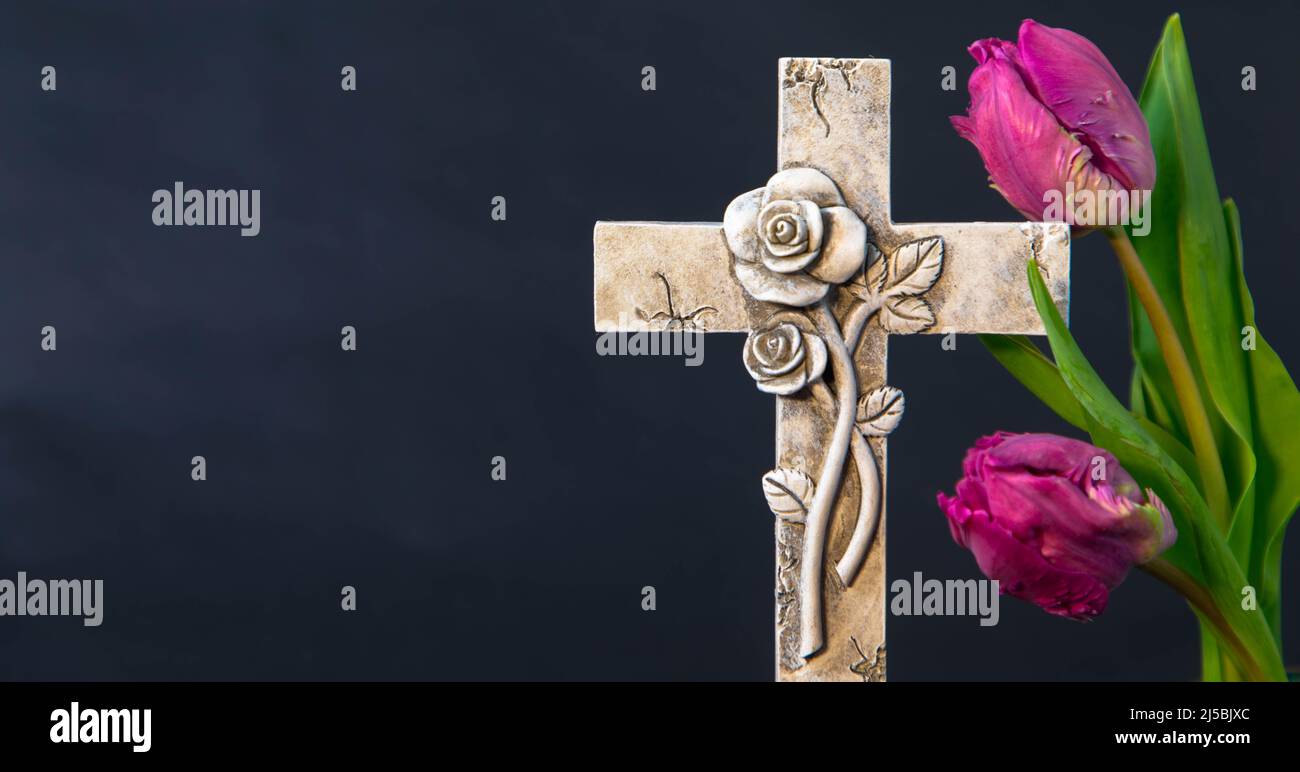 Croix religieuse avec fleurs de tulipe sur fond sombre pour avis nécrologique. Il y a beaucoup d'espace pour copier des paroles religieuses. Carte de condoléances, Banque D'Images