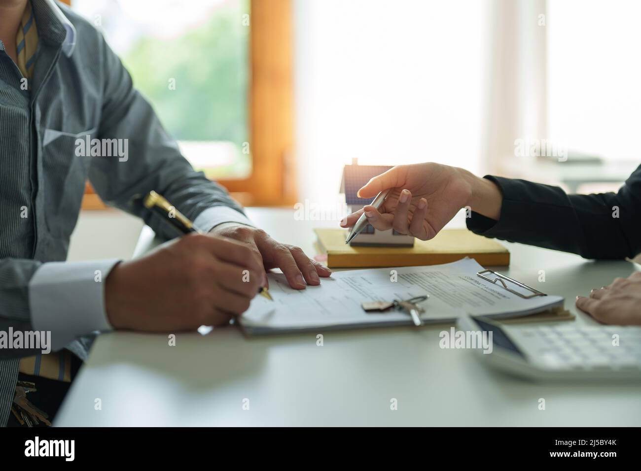 Les agents immobiliers acceptent d'acheter une maison et de donner des clés aux clients dans les bureaux de leur agence. Accord de concept Banque D'Images