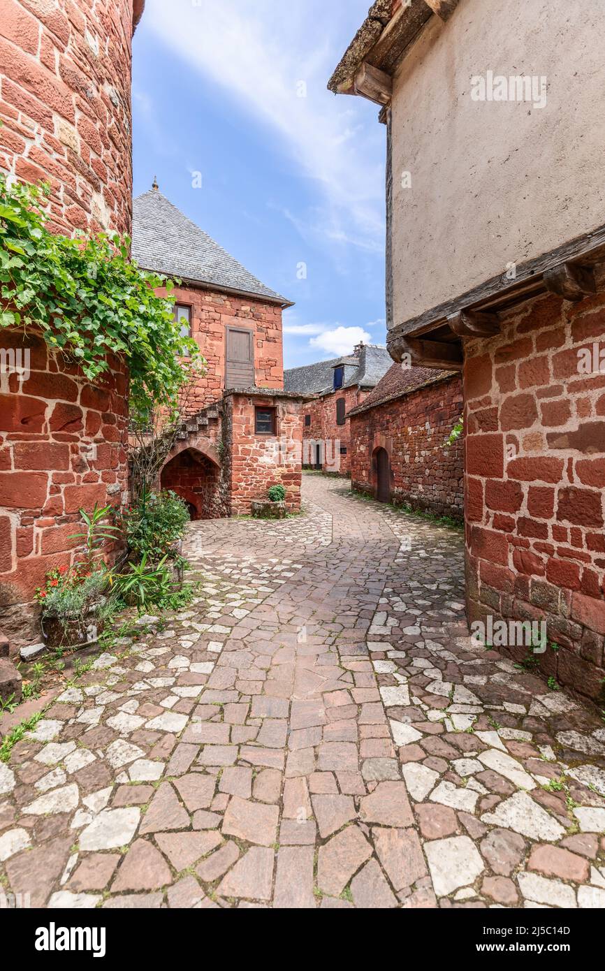 Chaussée en pierre déserte entre d'anciennes maisons en pierre rouge d'architecture complexe à Collonges-la-Rouge, département de Corrèze, France Banque D'Images