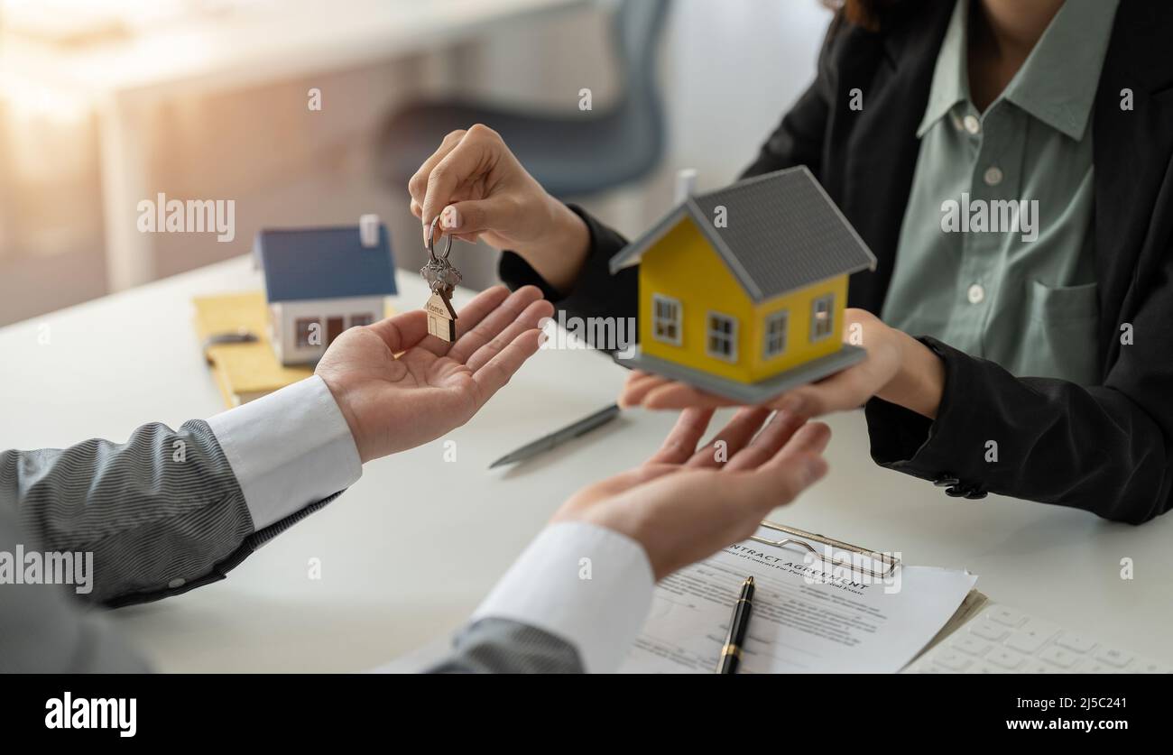 Homme prenant les clés de l'agent immobilier féminin pendant la réunion après la signature du contrat de location ou du contrat d'achat de vente. Femme indépendante Banque D'Images