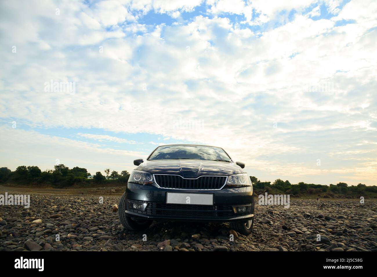 Voiture de sport noire sur la route rocheuse de rivière . Image de stock de paysage de voiture noire. Vue moderne sur la façade de la voiture. Sur fond de ciel. Banque D'Images