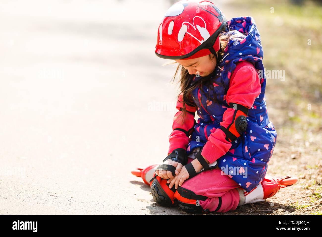 Fille avec casque mais sans protège-genoux pleurs Banque D'Images