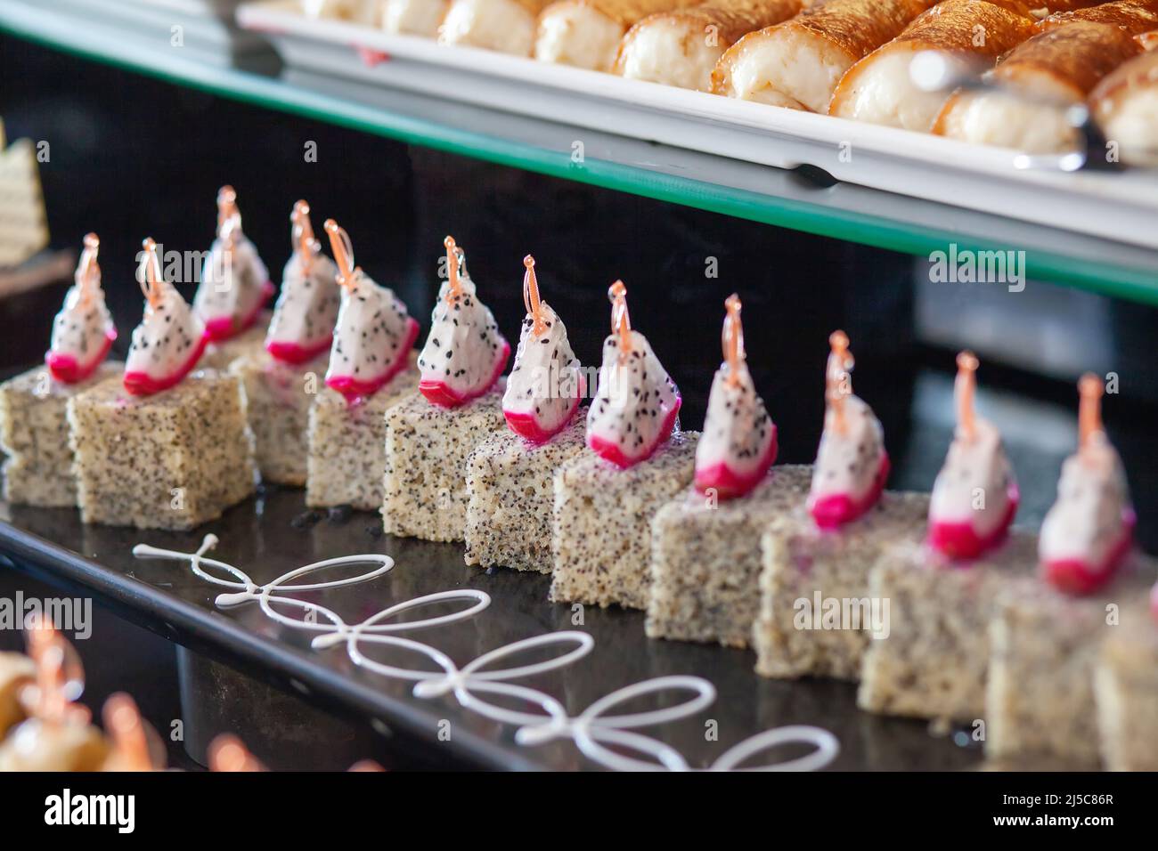 Génoise aux graines de pavot et aux tranches de fruits de dragon. Table de desserts dans un hôtel turc. Divers gâteaux et bonbons sont servis sous forme de buffet. Banque D'Images