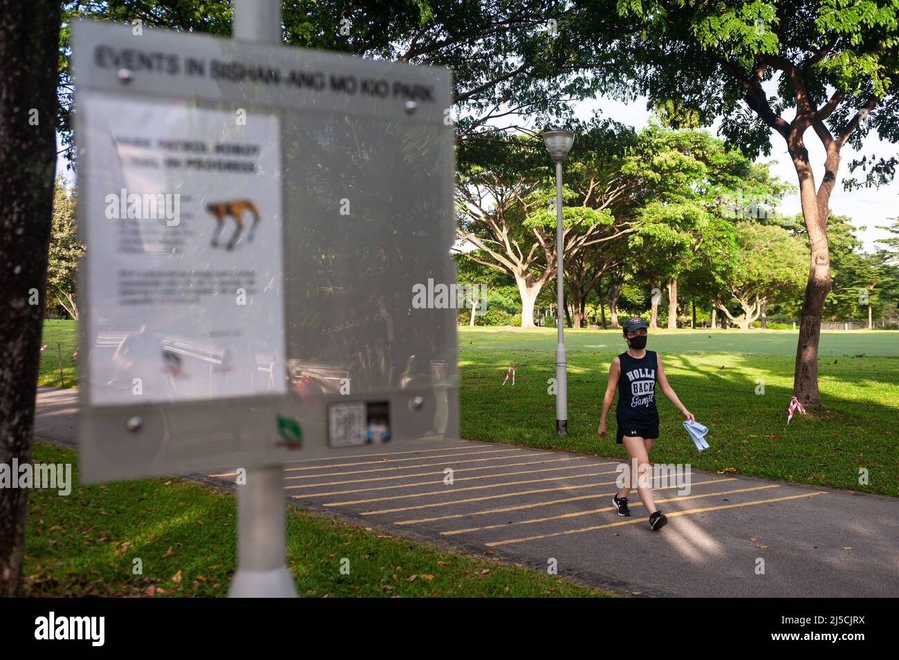Le 15 mai 2020, Singapour, République de Singapour, Asie - Une femme portant un protège-bouche passe devant un panneau dans le parc Bishan-Ang Mo Kio pour informer du déploiement d'une patrouille robotique à des fins d'étude dans le cadre de mesures de distance sûres au milieu de la crise de Corona (Covid-19). [traduction automatique] Banque D'Images