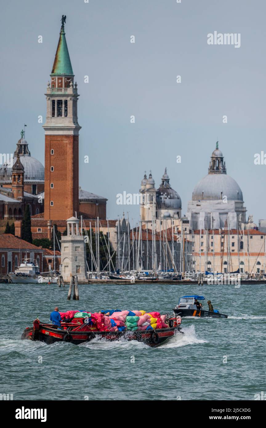 Un bateau avec des sacs de déchets sur la Canale di San Marco en face de l'église de San Giorgio Maggiore sur la Canale di San Marco - les canaux sont les principales artères portant toutes les formes de transport de l'eau - Venise au début de la Biennale di Venezia à 2022. Banque D'Images