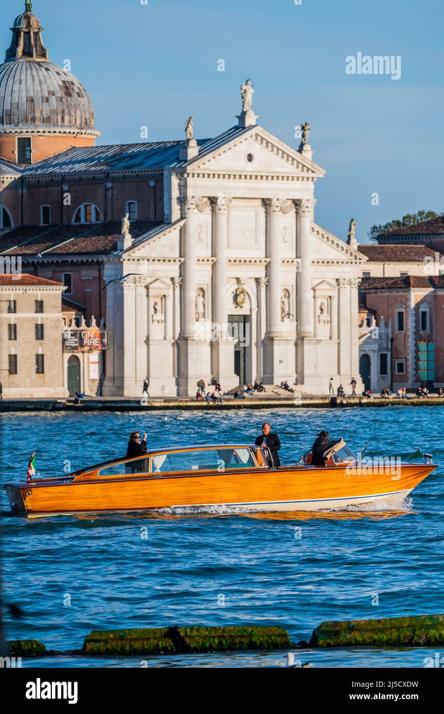 Un bateau-taxi en bois verni passe l'église de San Giorgio Maggiore - les canaux sont les artères principales portant toutes les formes de transport d'eau - Venise au début de la Biennale di Venezia en 2022. Banque D'Images