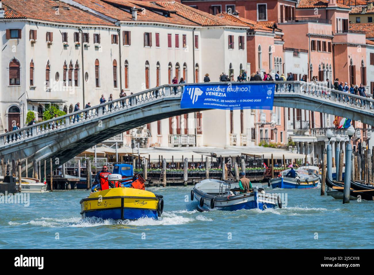 Les bateaux de travail transportent des déchets (dans les couleurs ukraniennes) et des marchandises sur le Grand Canal - les canaux sont les principales artères portant toutes les formes de transport d'eau - Venise au début de la Biennale di Venezia en 2022. Banque D'Images