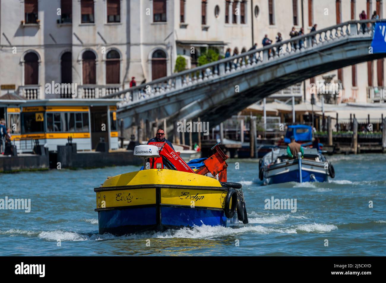 Les bateaux de travail transportent des déchets (dans les couleurs ukraniennes) et des marchandises sur le Grand Canal - les canaux sont les principales artères portant toutes les formes de transport d'eau - Venise au début de la Biennale di Venezia en 2022. Banque D'Images