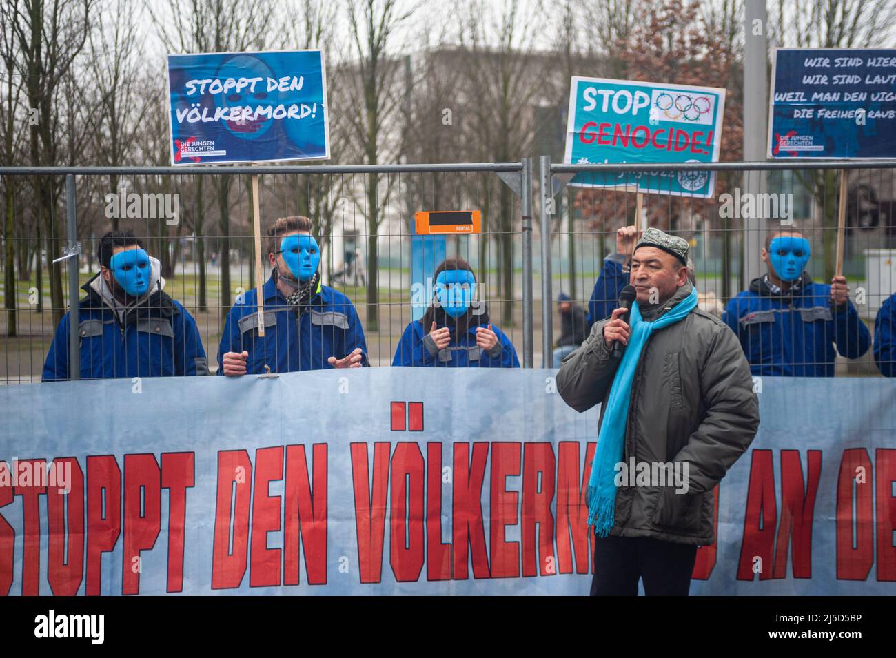 29 janvier 2022, Berlin, Allemagne, Europe - Asgar CAN, président de l'Union du Turkestan oriental (communauté Uyghur), prenant la parole lors d'un rassemblement devant la Chancellerie fédérale dans le district de Berlin-Mitte. Derrière eux, des manifestants masqués du groupe d'activistes les jeunes justes protestent avec des bannières et des affiches de protestation contre le génocide des Oughours dans la région autonome chinoise du Xinjiang et le respect des droits de l'homme et exigent un boycott diplomatique des Jeux olympiques d'hiver de 2022 à Beijing. [traduction automatique] Banque D'Images