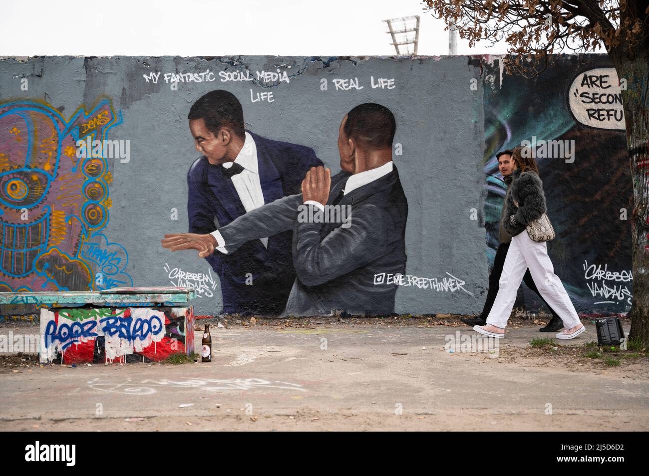 '30.03.2022, Berlin, Allemagne, Europe - Un graffiti de l'artiste Eme Freethinker sur un segment du mur de Berlin dans le Mauerpark de Berlin, dans le quartier de Prenzlauer Berg, montre l'acteur Will Smith qui claque le comédien Chris Rock lors des Academy Awards 94th après avoir fait du plaisir à son épouse Jada Pinkett Smith. Will Smith remporte plus tard le premier Oscar de sa carrière pour le rôle du père des joueurs de tennis venus et Serena Williams dans le film ''King Richard''. [traduction automatique]' Banque D'Images