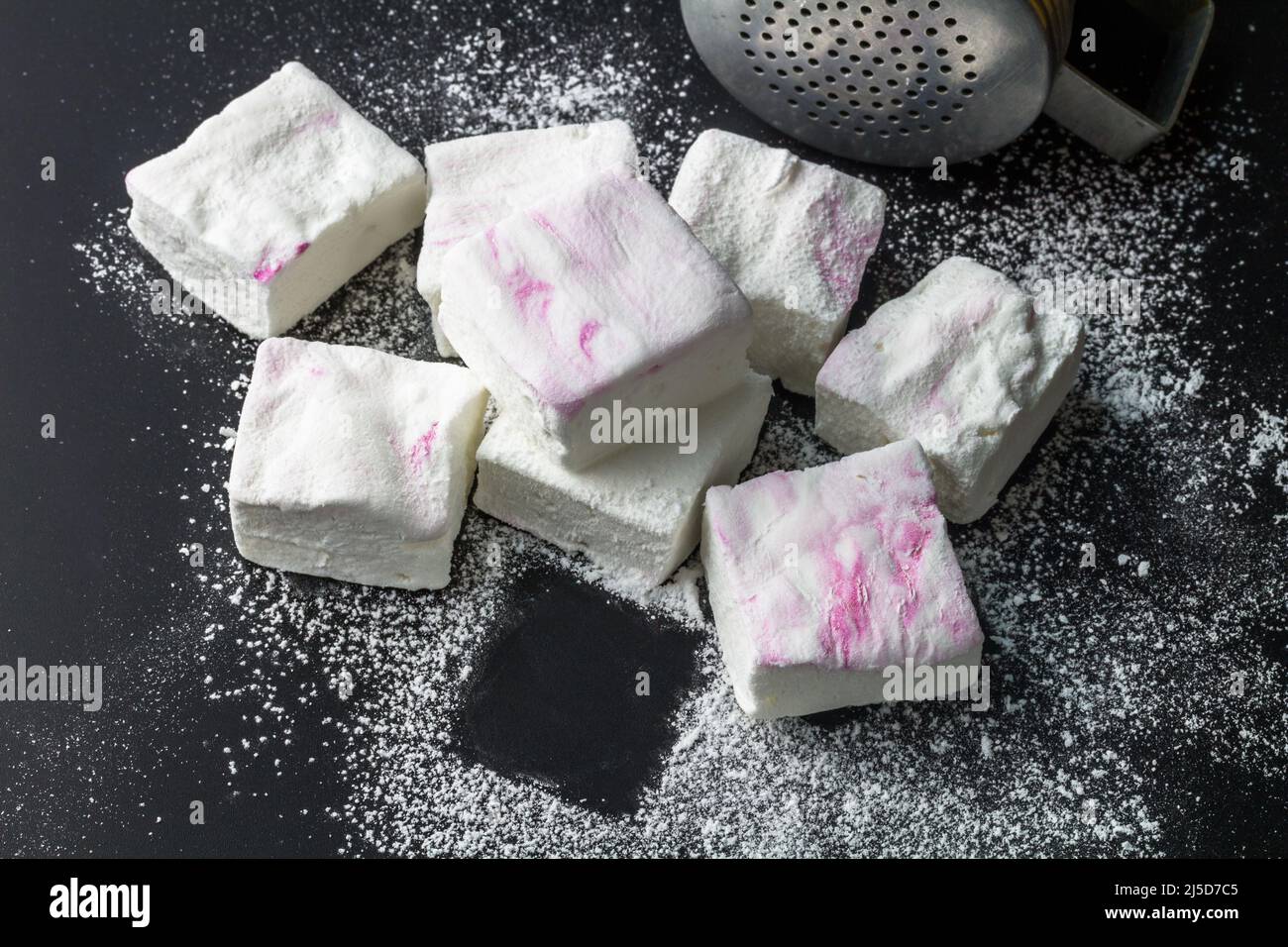 Guimauves roses et blanches faites maison - guimauves saupoudrées de sucre sur fond noir avec espace de copie Banque D'Images