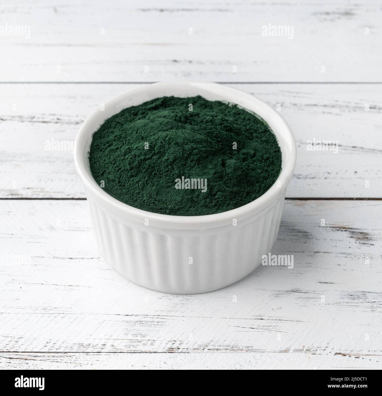 La poudre d'algues spiruline dans un bol sur une table en bois. Banque D'Images