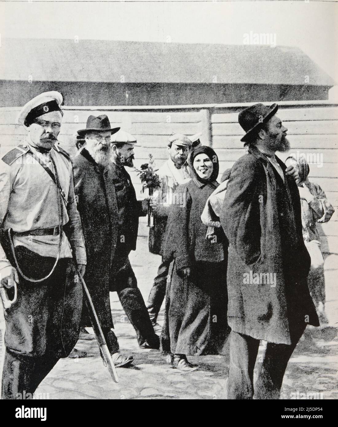 Traduction ENG : ' RÉVOLUTIONNAIRES RUSSES départ pour la Sibérie d'un groupe de condamnés politiques: L'un d'eux porte un bouquet qu'un ami lui a donné; une femme reste la langue du photographe.' - Original en français : ' REVOLUTIONNAIRES RUSSES Départ pour la Sibérie d'un groupe de composants politiques : l'un d'eux porte un bouquet qu'un ami lui a offert ; une femme pneu la langue au photographe.' - Extrait de 'l'Illustration Journal universel' - magazine illustré français - 1906 Banque D'Images