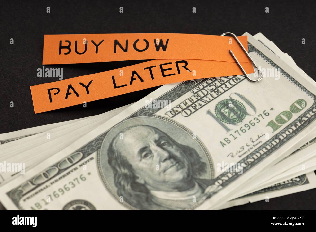 Concept BNPL ou Buy Now Pay later. Billets en dollars et étiquette avec message sur fond noir Banque D'Images