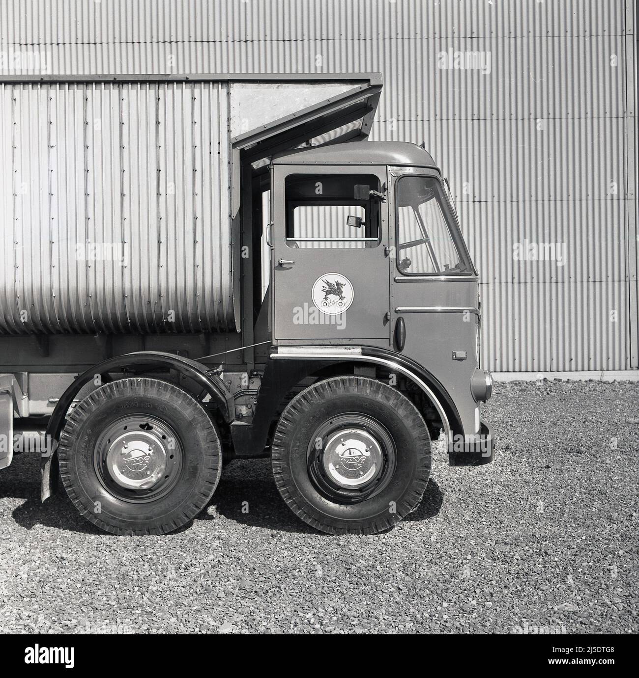 1950s, vue latérale historique de l'avant d'un camion de camion-benne ou d'un camion-tracteur de la compagnie d'acier du pays de Galles, Abbey Works, Port Talbot, pays de Galles, Royaume-Uni. Le logo de la société d'un dragon gallois fièrement debout sur deux rouleaux d'acier pressé est visible sur la porte de la cabine du conducteur. Les aciéries géantes construites sur les anciennes aciéries Margam, produisent toutes sortes d'acier et de fer, y compris des tôles laminées à chaud et à froid et des bobines pour carrosseries automatiques et d'autres types d'acier à utiliser dans l'industrie et les chemins de fer. Banque D'Images