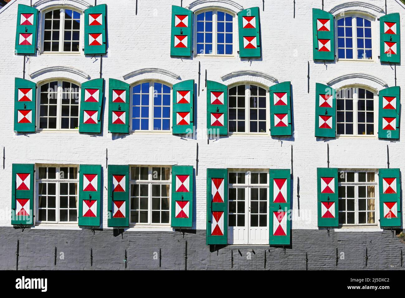 Gros plan de l'ancienne façade de la maison, de nombreuses fenêtres en verre, des volets en bois ouvert en extérieur peints en triangle rouge blanc - Lier, Belgique Banque D'Images