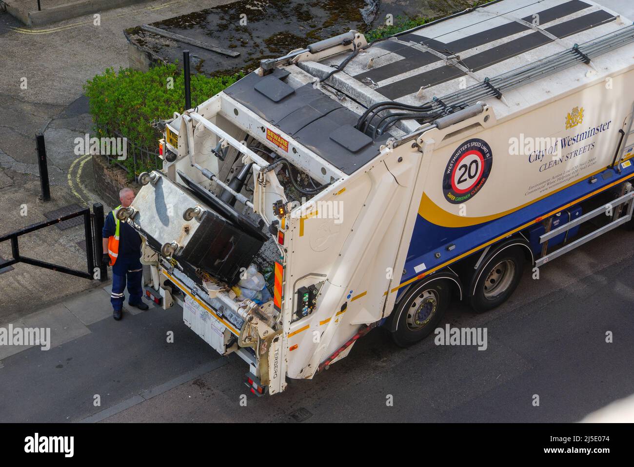 Londres, Royaume-Uni-17.04.22 : un homme déchargeant un conteneur de déchets dans un camion-chargeuse arrière dans une ville de Westminster, dans le centre de Londres Banque D'Images