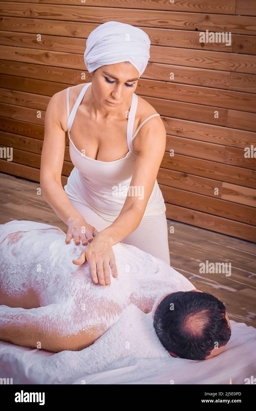 Une femme guérisseur exécute un rituel avec du sel, frotte le dos d'un homme couché avec du sel. Détente. Banque D'Images