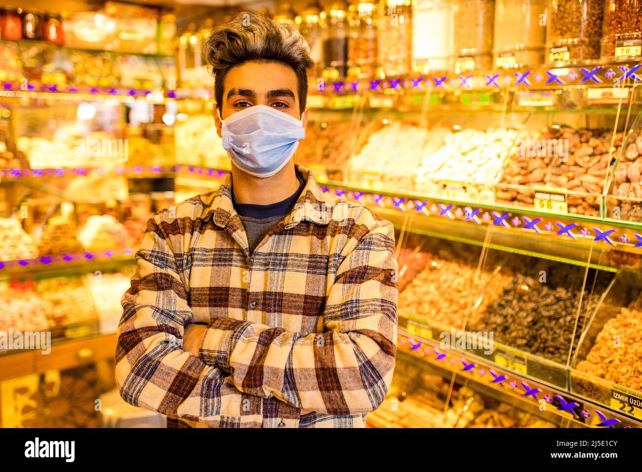 beau homme arabe porter masque médical vendeur sucreries dans son bazar de magasin Banque D'Images