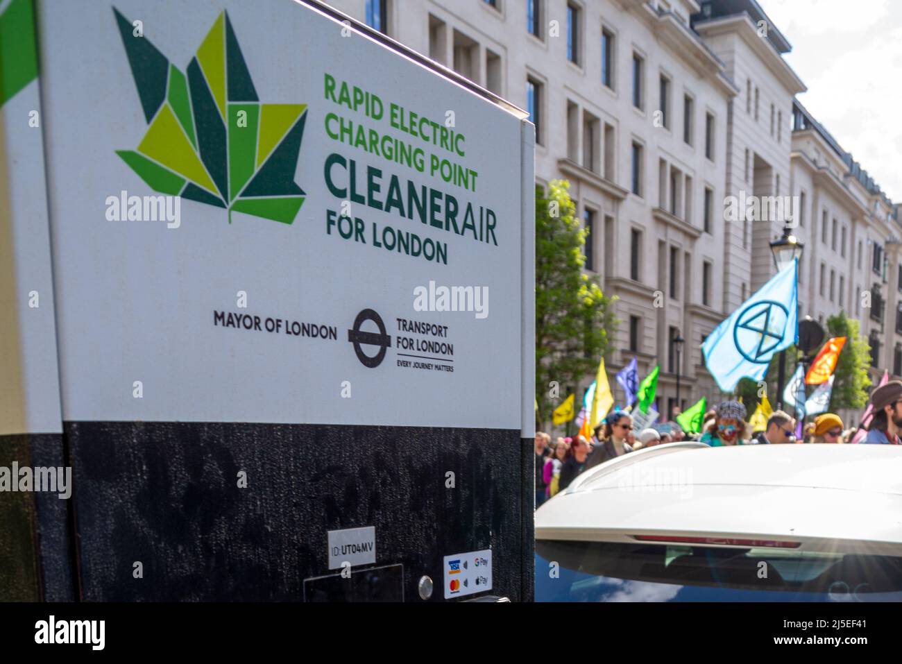 Extinction les manifestants de la rébellion passent devant un point de chargement de voiture électrique, se dirigeant vers le siège de BP pour protester contre les combustibles fossiles. Texte « CLEANER air » Banque D'Images