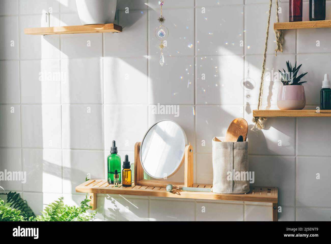 Cristal de cacheron de soleil faisant beaucoup de poutres de somme et de taches de lumière sur le mur de tuiles blanches à la journée ensoleillée. Salle de bains moderne écologique au design minimaliste biophile Banque D'Images