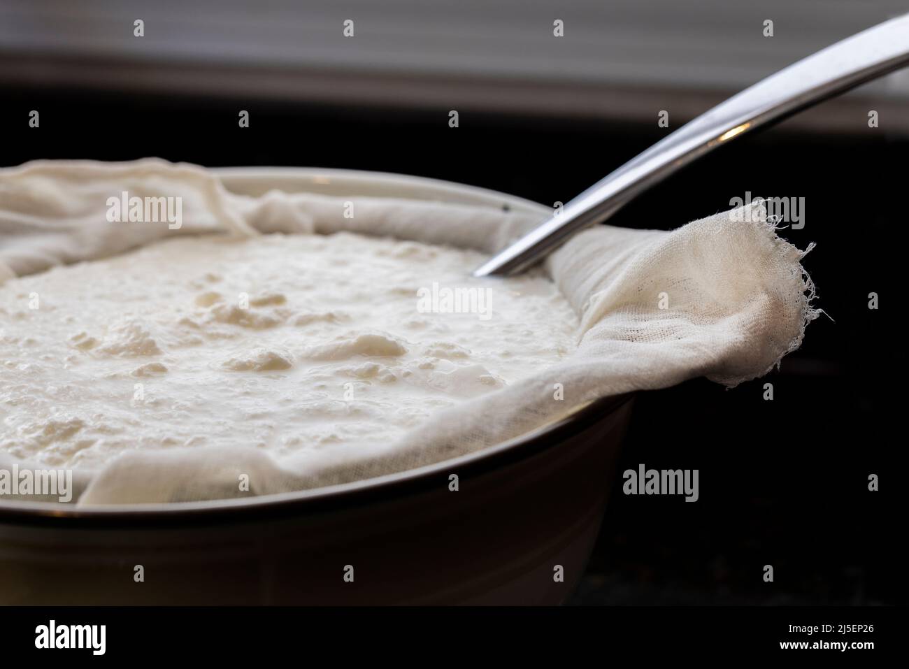 Séparer le lactosérum du yaourt maison avec un cheesecloth et une passoire dans un bol Banque D'Images