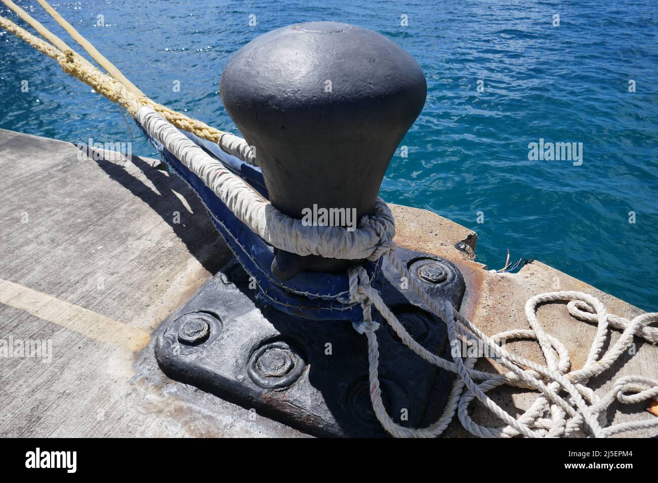 Grand navire de mer amarre bollard sur quai en béton avec des cordes d'ancrage attachées Banque D'Images