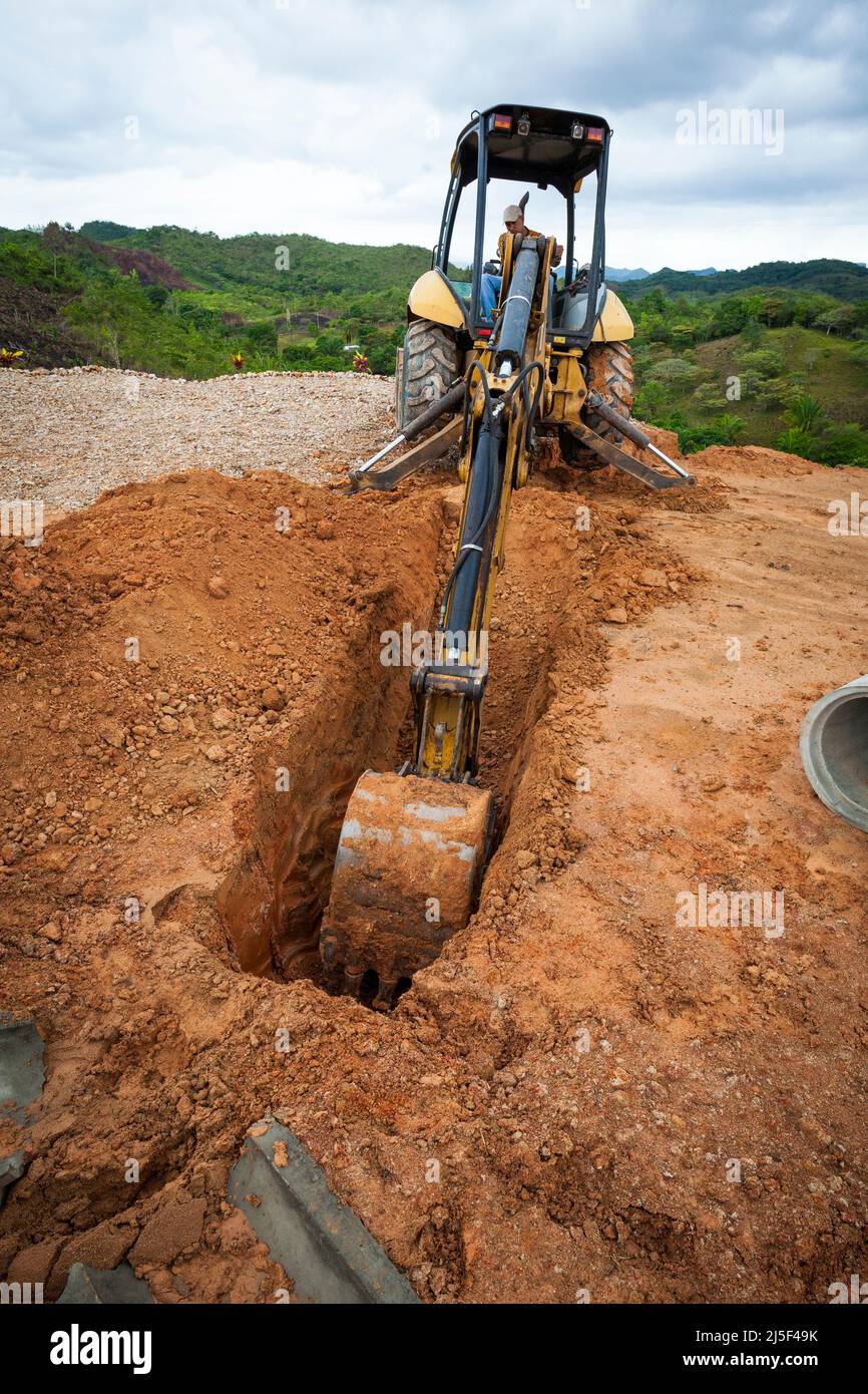 Un conducteur de pelle hydraulique équipé d'une pelle hydraulique creuse un fossé sur un chantier de construction à Las Minas de Tulu, province de Cocle, République du Panama. Banque D'Images