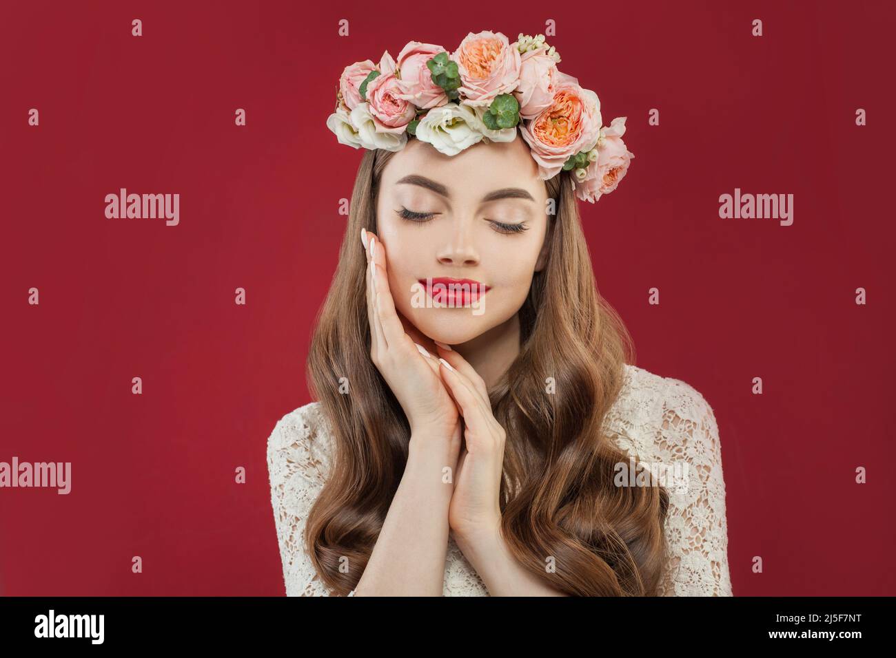 Belle jeune femme avec fleurs roses d'été, cheveux longs permed et maquillage de mode Banque D'Images