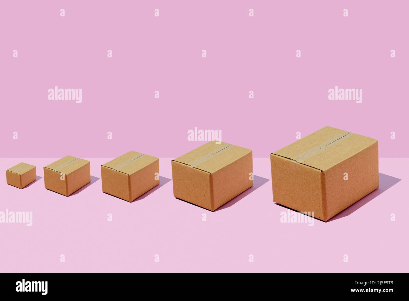 Boîtes en carton de différentes tailles rangées sur fond violet. Concept de livraison de colis. Banque D'Images