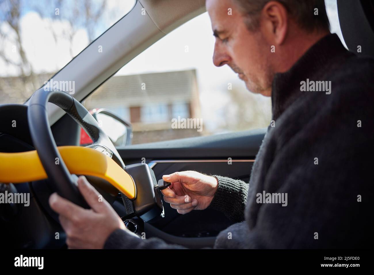Homme mature qui monte le verrouillage manuel du volant dans la voiture Banque D'Images