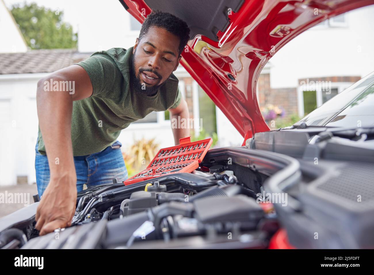Homme travaillant sous le capot d'une voiture fixant le moteur à l'aide d'une clé Banque D'Images