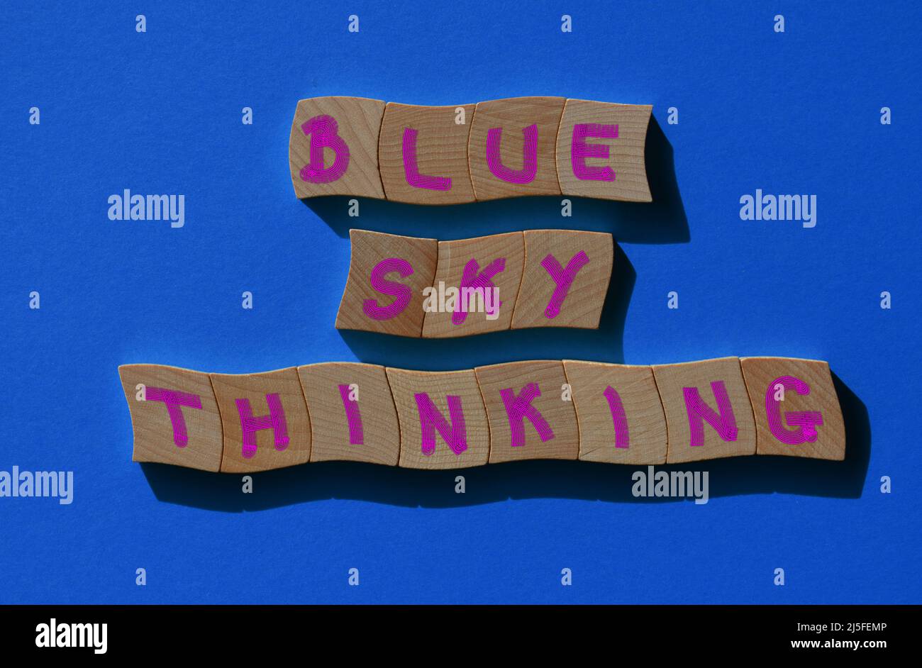 Blue Sky Thinking, phrase en lettres de l'alphabet de bois isolées sur fond bleu Banque D'Images