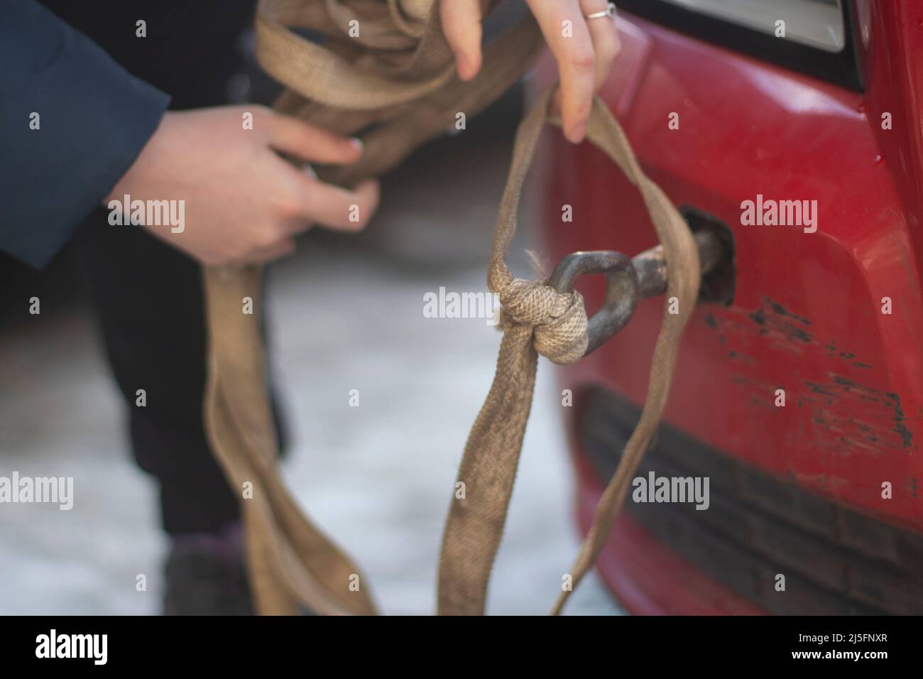 Câble pour voiture. Guy accroche la voiture pour le remorquage. Mains tient le mousqueton pour visser dans le pare-chocs de la voiture. Préparation de l'évacuation du véhicule. Banque D'Images