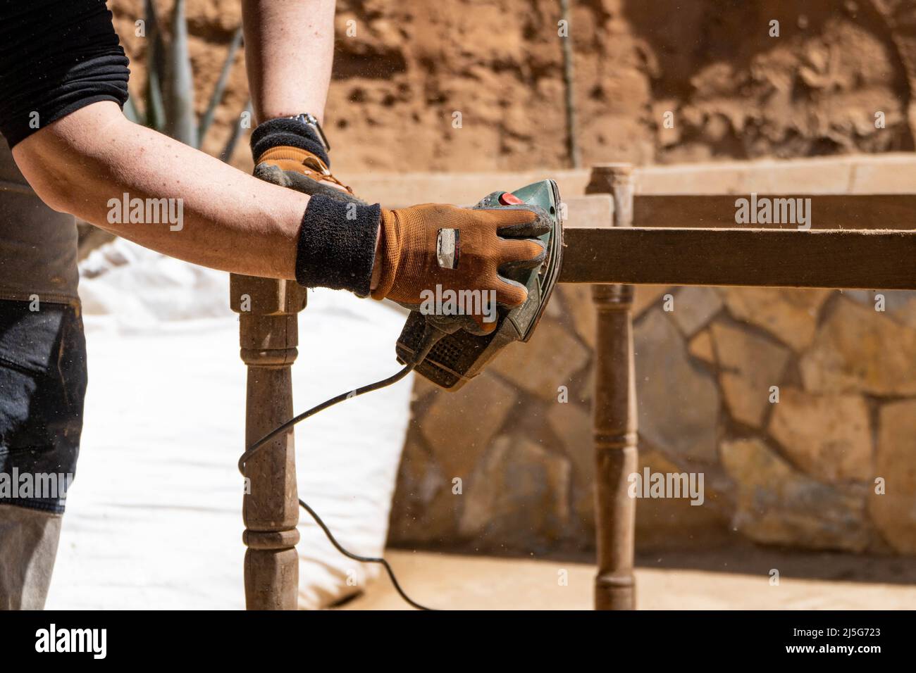 Homme travaillant sur la restauration des anciennes forniture à l'aide d'une ponceuse électrique. Concept de l'entretien du bois et de l'imperméabilisation Banque D'Images