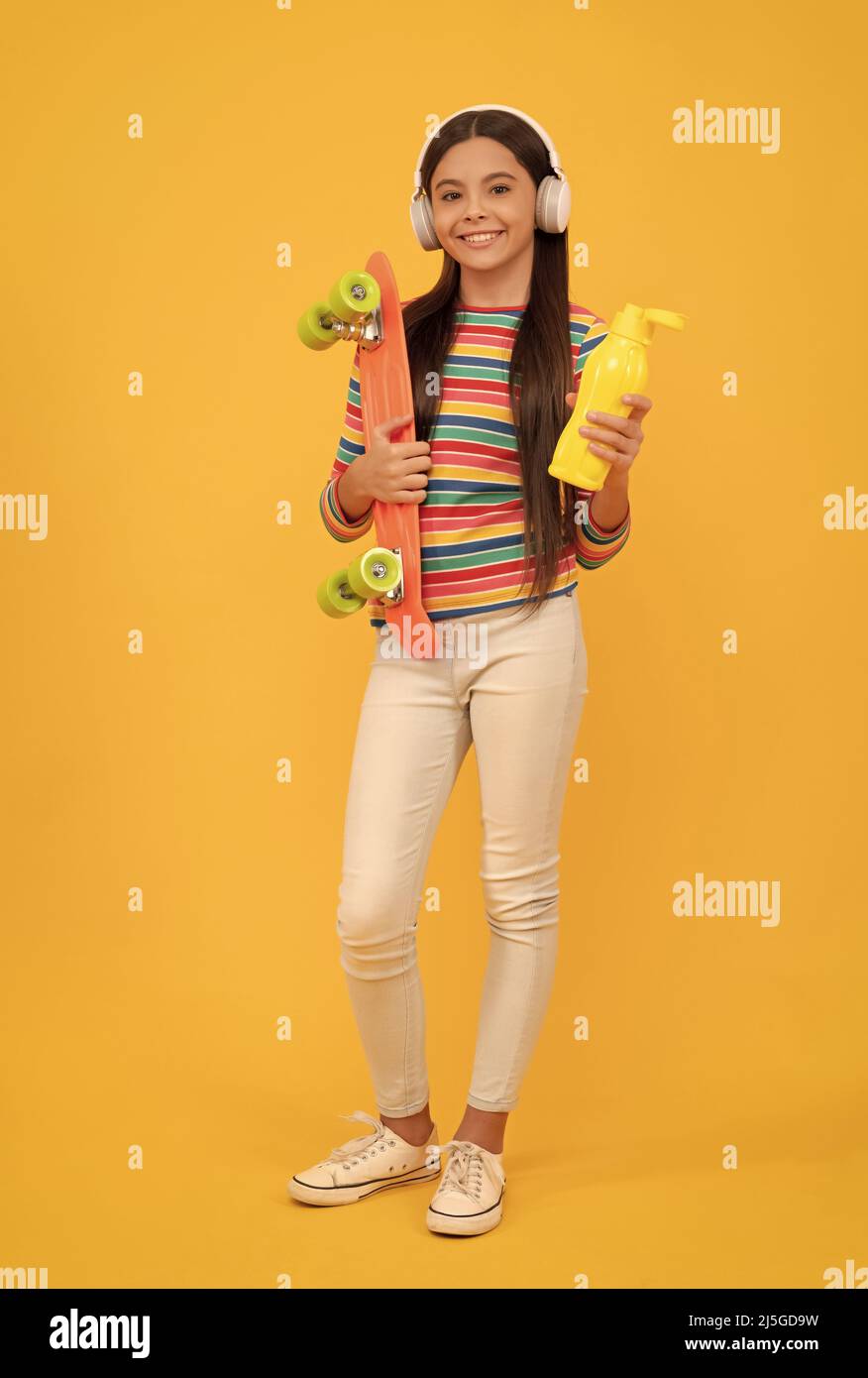 skateboard. enfant heureux dans un casque avec planche de sou. jeune fille écoute de la musique. Banque D'Images