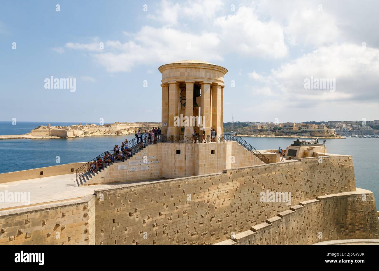Un groupe de touristes assis sur les marches du mémorial du Siege Bell, la Valette, Malte Banque D'Images