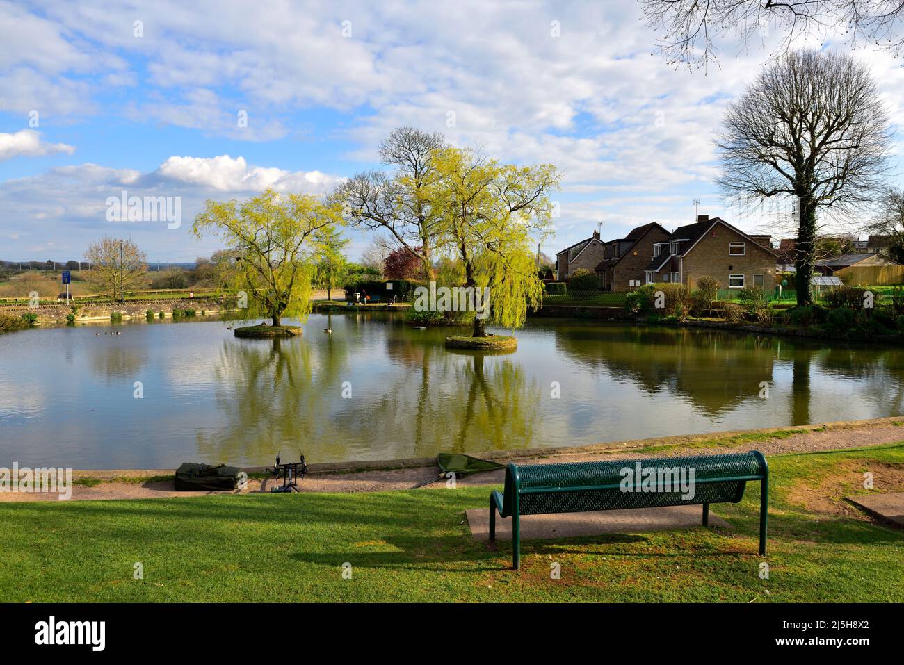 Place assise sur le green surplombant le village de Winterbourne Duck Pond, Bristol, Royaume-Uni Banque D'Images