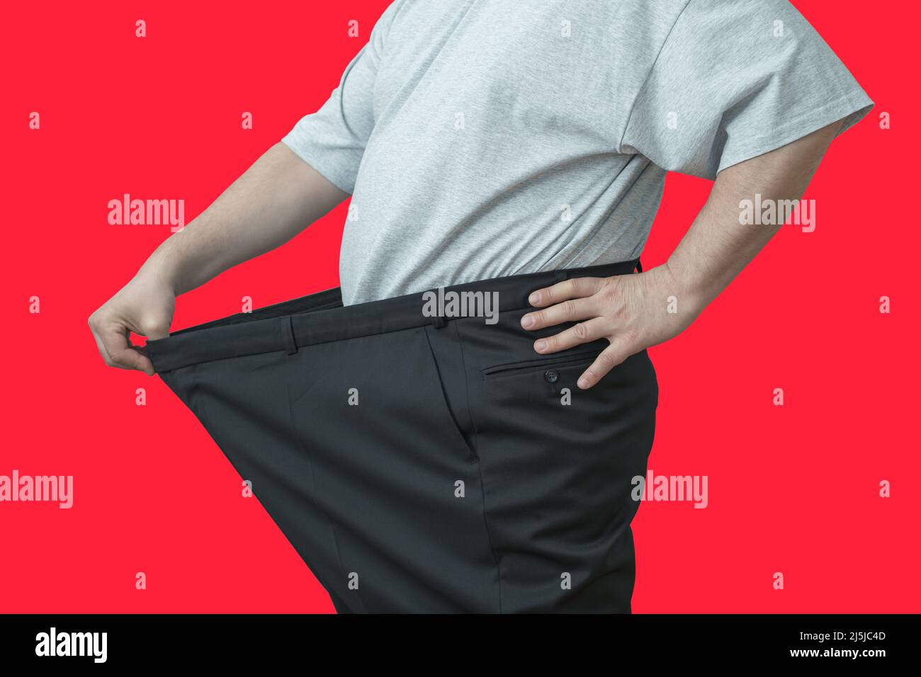 L'homme tire sur son grand pantalon à la taille. Montre comment il a perdu du poids. Banque D'Images