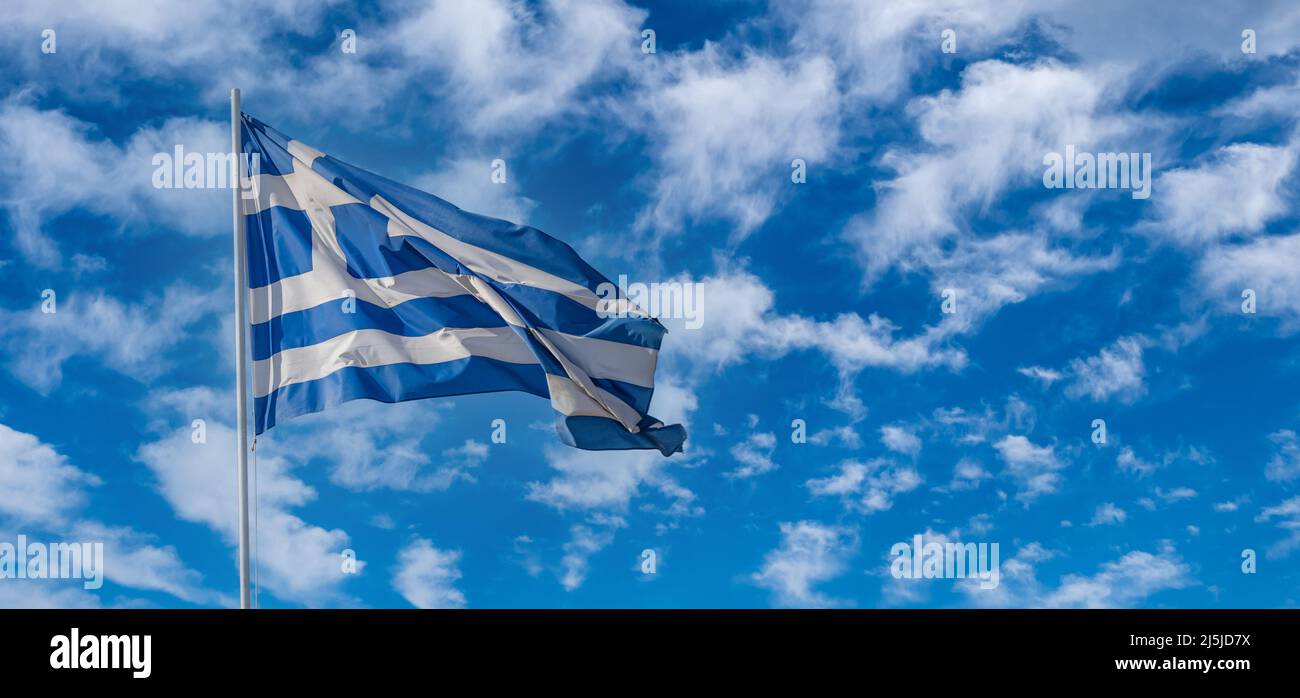 Drapeau officiel national grec sur le mât agitant dans le vent. Symbole de la Grèce. Ciel bleu ciel nuageux, jour de printemps ensoleillé à Athènes. Banque D'Images