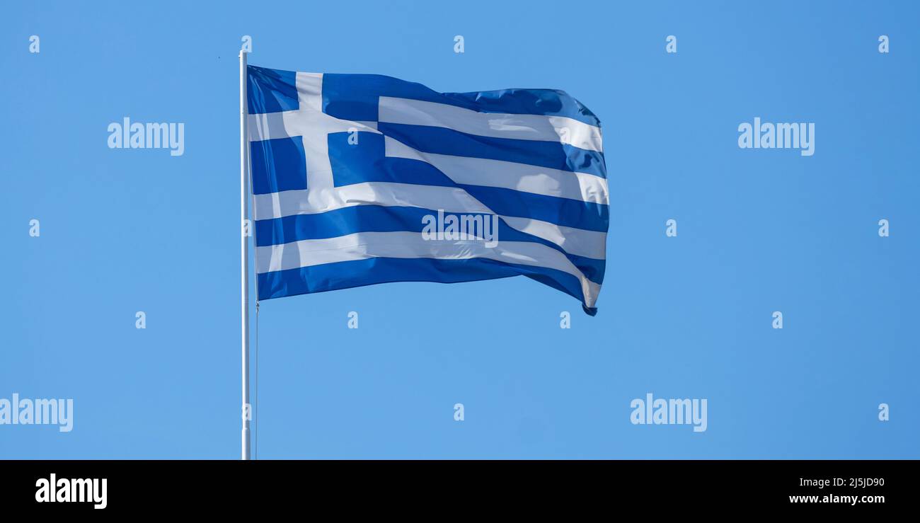 Symbole de la Grèce. Drapeau officiel national grec sur le mât agitant dans le vent. Ciel bleu clair, jour de printemps ensoleillé à Athènes. Banque D'Images