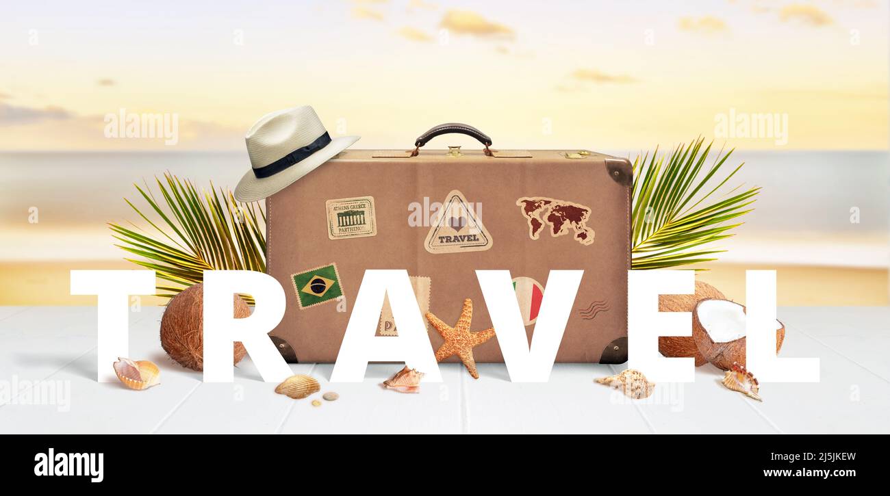 Texte de voyage devant une valise rétro avec autocollants de voyage sur la plage entourée de feuilles de palmier, noix de coco et coquillages Banque D'Images