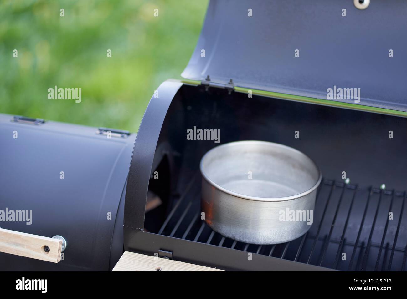 Nouveau barbecue fumeur. Récipient contenant de l'eau dans une chambre ouverte, empêche le séchage des aliments grillés. Banque D'Images