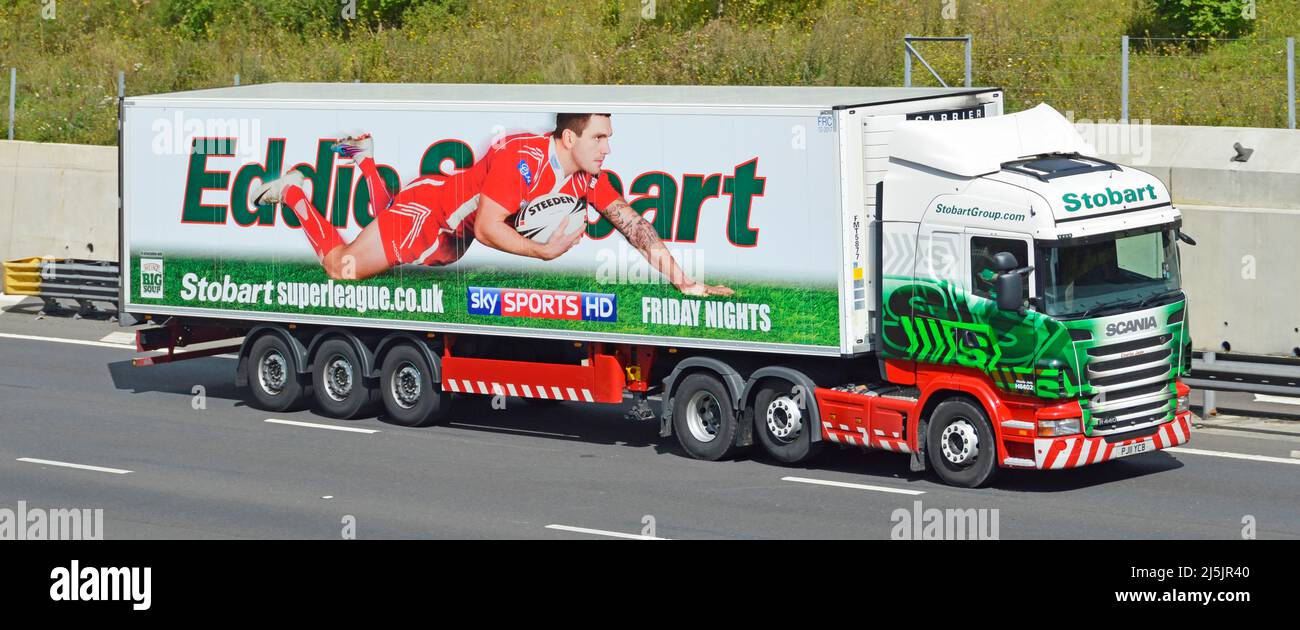 Vue latérale avant Stobart Group SCANIA hgv camion et remorque articulée publicité graphique Eddie Stobart Super League sponsoring sur l'autoroute britannique Banque D'Images