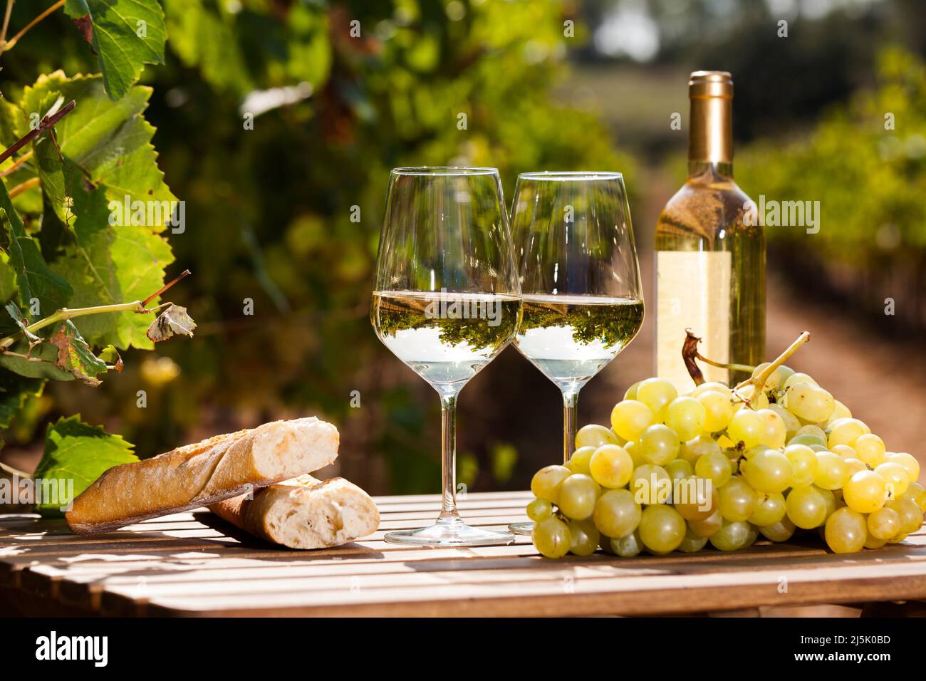 Verre de vin blanc raisins mûrs et pain sur table dans le vignoble Banque D'Images