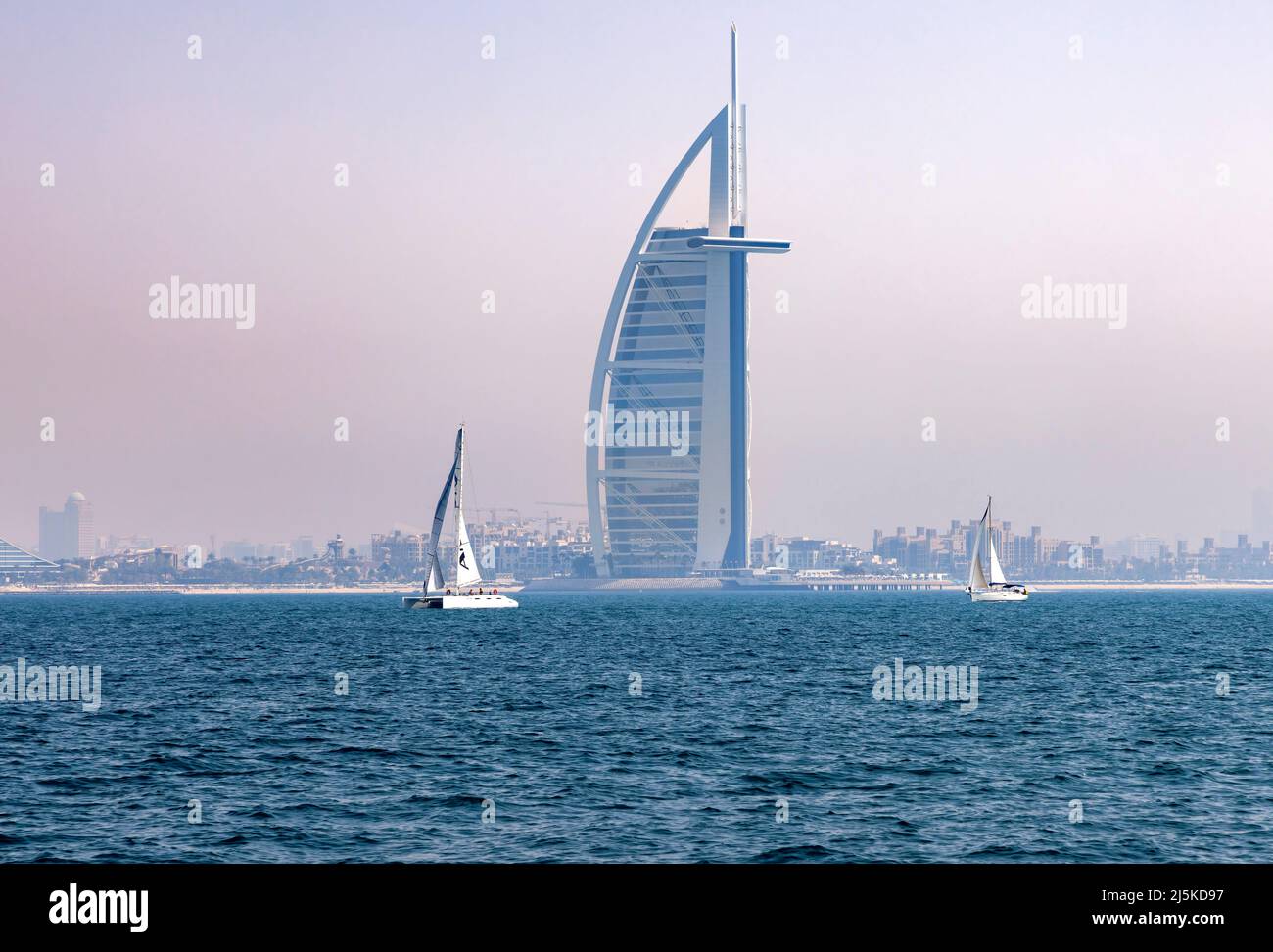 DUBAI, ÉMIRATS ARABES UNIS - 9 AVRIL : les voiliers passent devant l'hôtel Burj Al Arab à Jumeirah Beach le 9 avril 2022 à Dubaï, Émirats Arabes Unis. La ville est souvent couverte par un mélange de sable et de vapeur du désert pendant les saisons chaudes. Banque D'Images