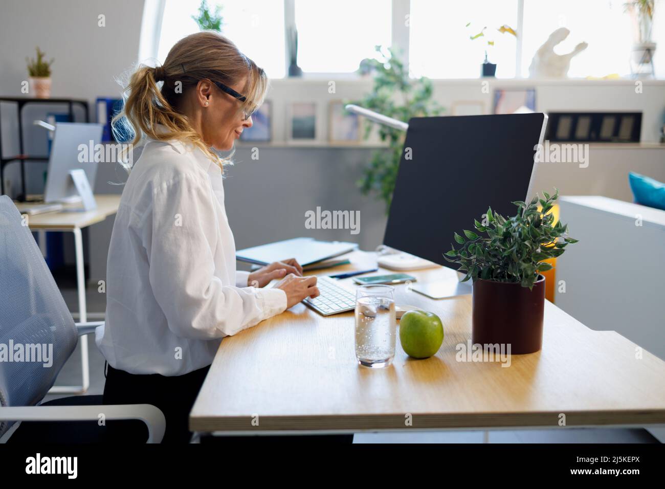 Femme d'affaires élégante et mûre travaillant sur un ordinateur au bureau Banque D'Images