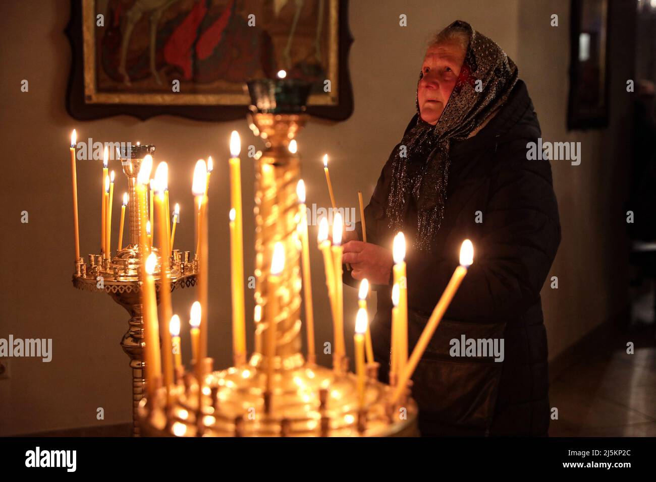 BUCHA, UKRAINE - AVRIL 24, 2022 - Une femme âgée tient une bougie allumée pendant une liturgie de Pâques dans l'Église de Saint Andrew l'Apôtre premier-appelé pendant la célébration orthodoxe de Pâques à Bucha qui se remet des crimes de guerre commis par les troupes russes après sa libération des envahisseurs russes, région de Kiev, dans le nord de l'Ukraine. Credit: UKRINFORM/Alamy Live News Banque D'Images