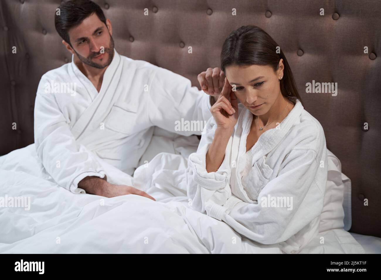 Femme en colère au lit, consolée par son mari Banque D'Images