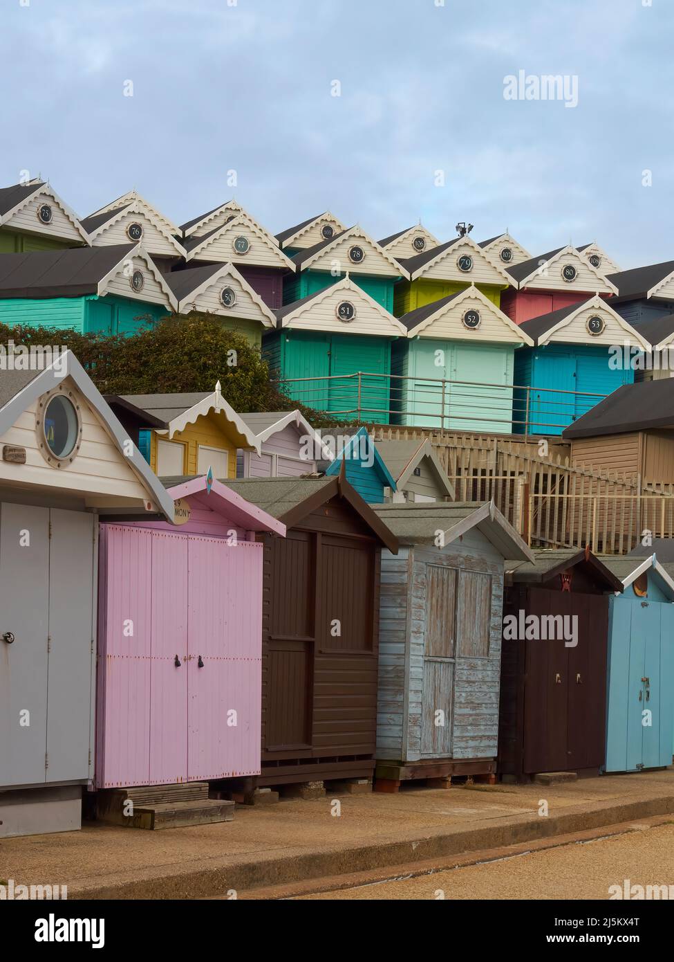 Niveaux de cabanes de plage en bois coloré, prêts pour les vacanciers, formant des motifs réguliers, géométriques, presque abstraits sur le bord de mer de Frinton-on-Sea. Banque D'Images